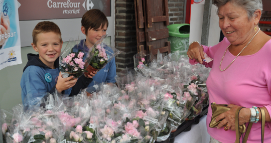 Een oudere vrouw en 2 jongens die bloemen verkopen